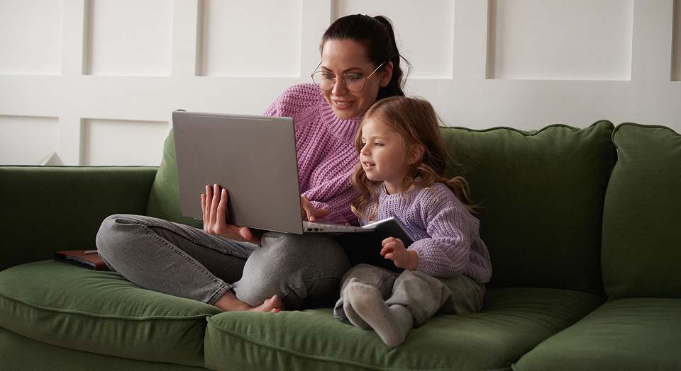 Mutter und Tochter sitzen auf Sofa